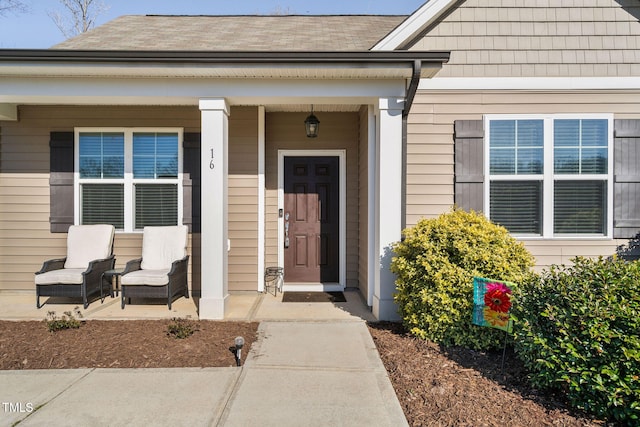 property entrance featuring covered porch and roof with shingles