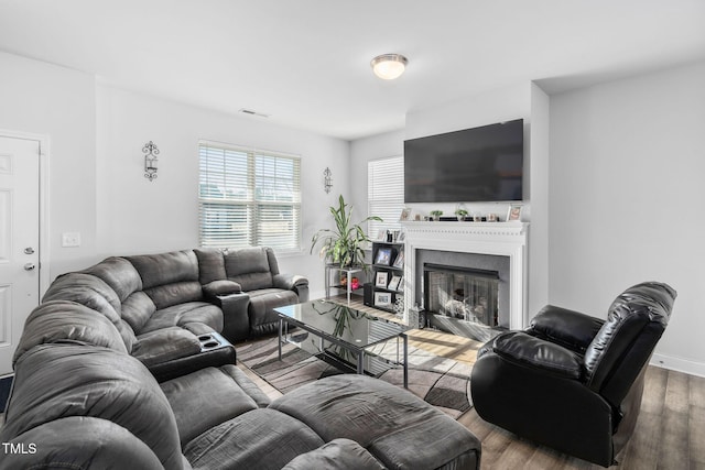 living area featuring a fireplace, wood finished floors, visible vents, and baseboards