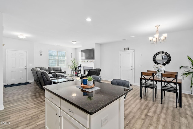 kitchen featuring a center island, open floor plan, light wood-style flooring, a notable chandelier, and white cabinetry