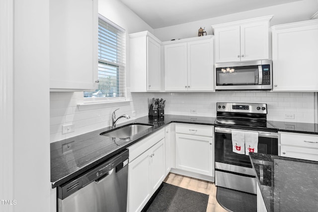 kitchen with a sink, light wood-style floors, appliances with stainless steel finishes, and white cabinetry