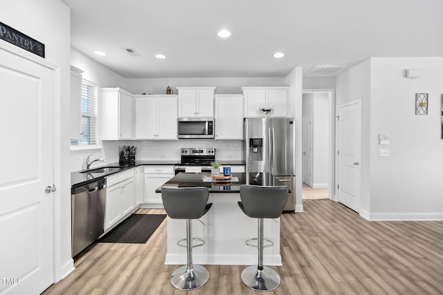 kitchen featuring light wood-type flooring, visible vents, a sink, a center island, and stainless steel appliances