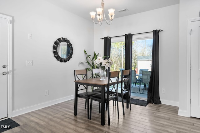 dining room with visible vents, wood finished floors, baseboards, and a chandelier