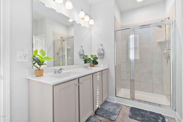 bathroom featuring double vanity, a stall shower, and a sink