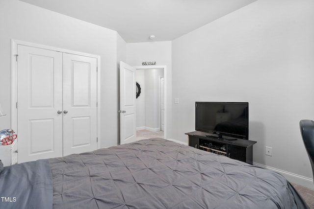 carpeted bedroom featuring a closet and baseboards