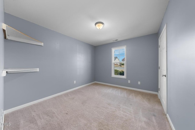 empty room with carpet flooring, visible vents, and baseboards