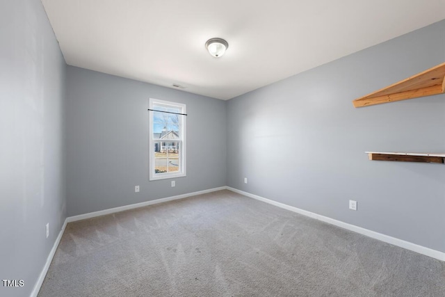 spare room featuring carpet flooring and baseboards