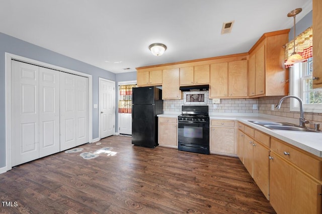 kitchen featuring light brown cabinets, dark wood-type flooring, under cabinet range hood, black appliances, and a sink