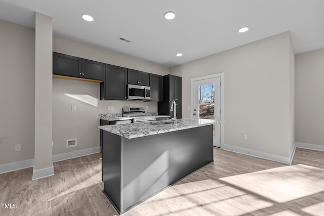 kitchen featuring light stone counters, recessed lighting, light wood finished floors, and stainless steel appliances