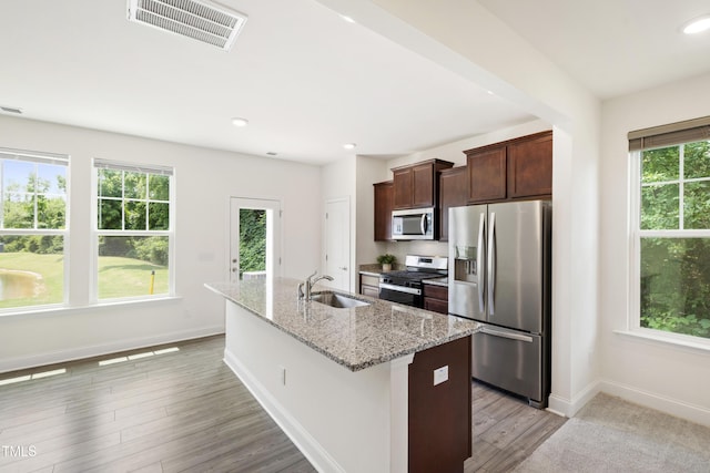 97 Begonia St, Angier, NC 27501 - kitchen with stainless steel appliances, a sink, a center island with sink, baseboards, and dark brown cabinetry