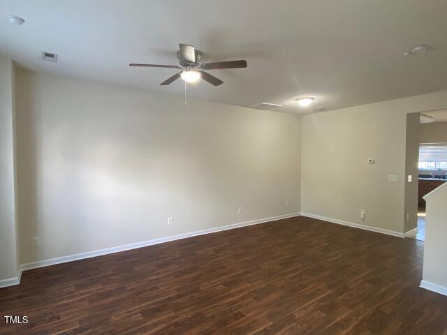 spare room with dark wood finished floors, baseboards, visible vents, and a ceiling fan