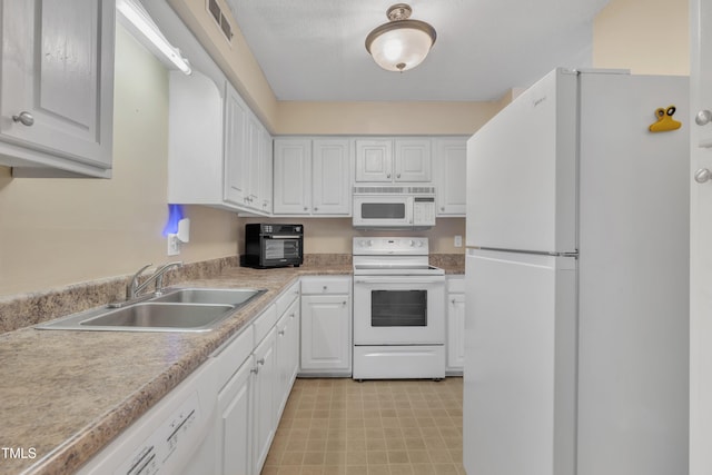 kitchen with white appliances, visible vents, a sink, light countertops, and white cabinetry