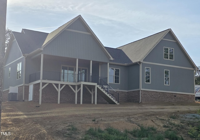 rear view of property featuring covered porch, roof with shingles, central AC unit, and stairs