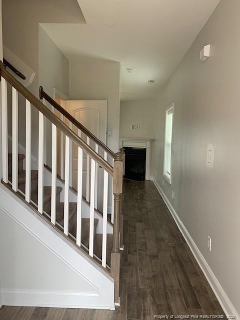 stairs featuring a fireplace, baseboards, and wood finished floors