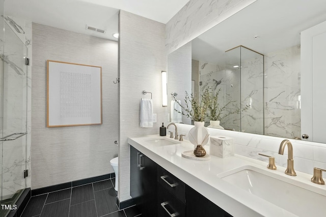 full bathroom featuring a sink, visible vents, a marble finish shower, and tile walls