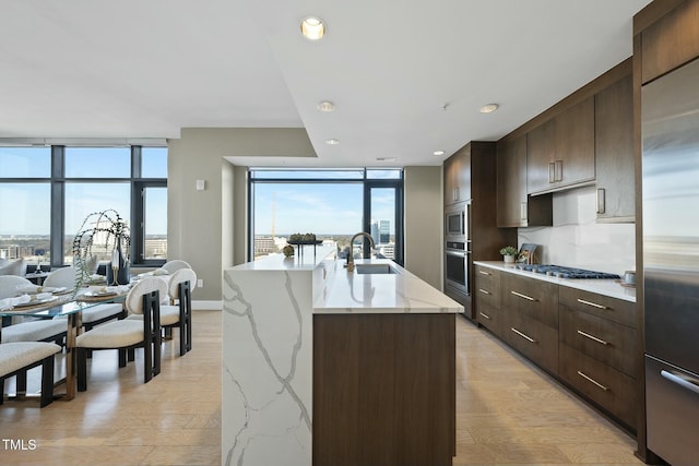 kitchen with built in appliances, dark brown cabinets, expansive windows, and a sink