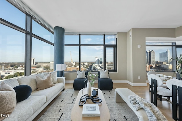 living area with expansive windows, a view of city, baseboards, and wood finished floors