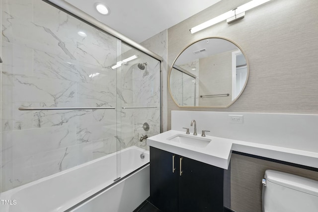 full bath featuring combined bath / shower with glass door, toilet, vanity, and visible vents