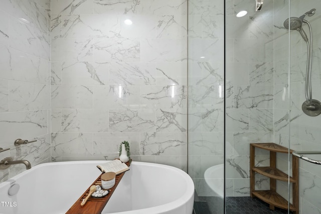 bathroom featuring tile walls, a walk in shower, and a freestanding bath