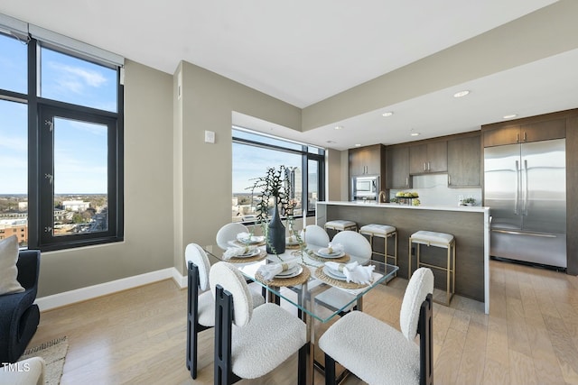 dining space featuring a wealth of natural light, recessed lighting, baseboards, and light wood-style floors