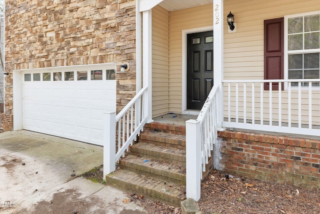 doorway to property featuring concrete driveway, a garage, and stone siding