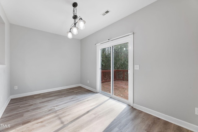 empty room with visible vents, baseboards, and wood finished floors