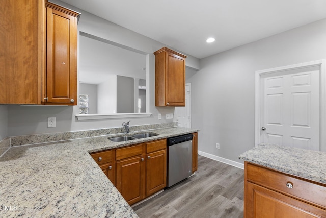 kitchen featuring brown cabinetry, dishwasher, light wood-style floors, and a sink