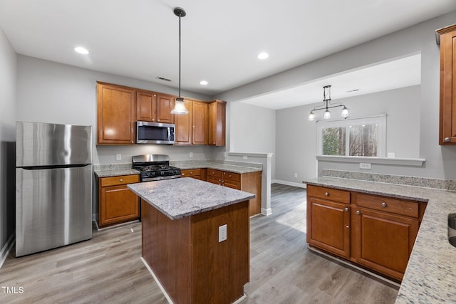 kitchen with light wood-type flooring, stainless steel appliances, a peninsula, and brown cabinetry