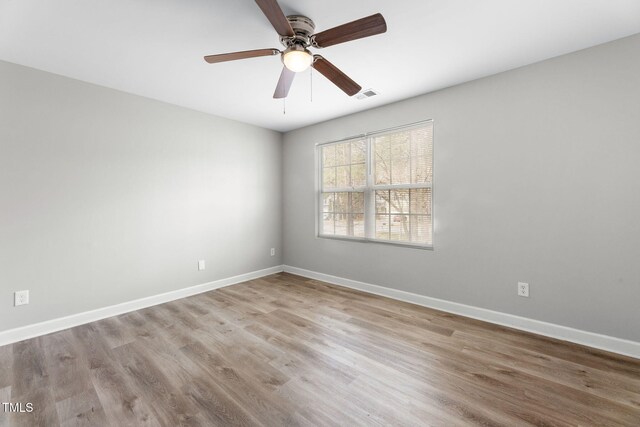 spare room with visible vents, baseboards, wood finished floors, and a ceiling fan