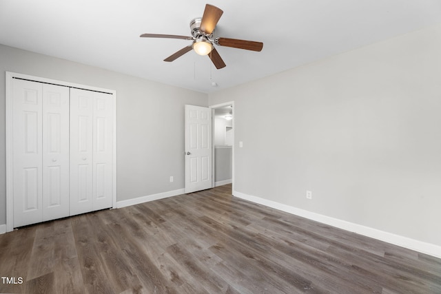 unfurnished bedroom featuring a closet, baseboards, wood finished floors, and a ceiling fan