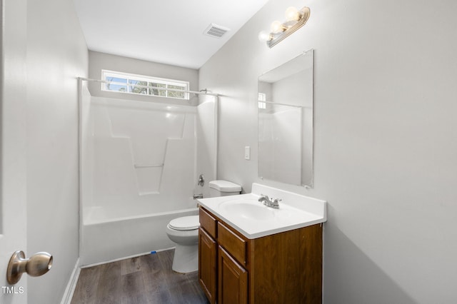 full bath featuring visible vents, toilet, wood finished floors, bathtub / shower combination, and vanity