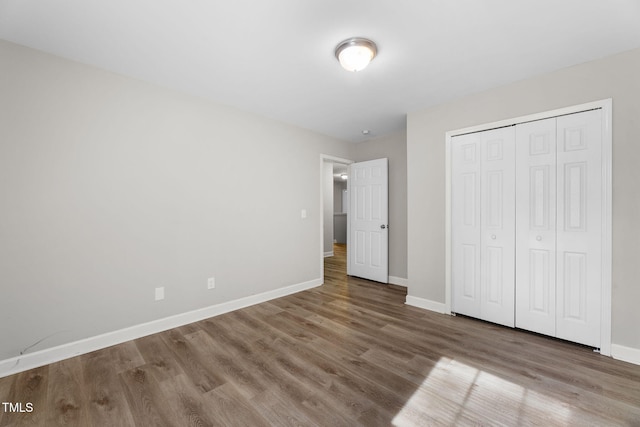 unfurnished bedroom with a closet, baseboards, and wood finished floors