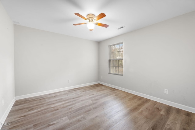 spare room with baseboards, wood finished floors, visible vents, and ceiling fan