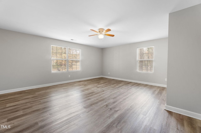 empty room with visible vents, wood finished floors, baseboards, and ceiling fan