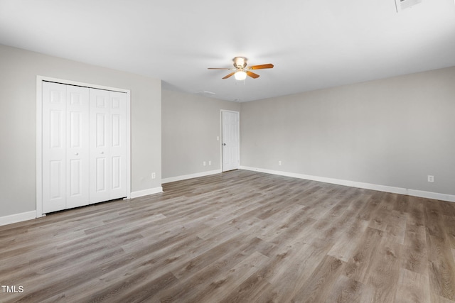 unfurnished bedroom with a closet, a ceiling fan, baseboards, and wood finished floors