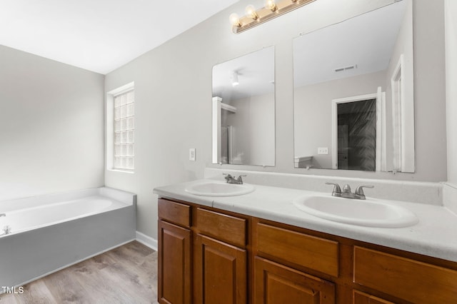 full bath featuring a sink, visible vents, a bath, and double vanity