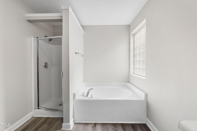 bathroom featuring a shower stall, a bath, wood finished floors, and baseboards