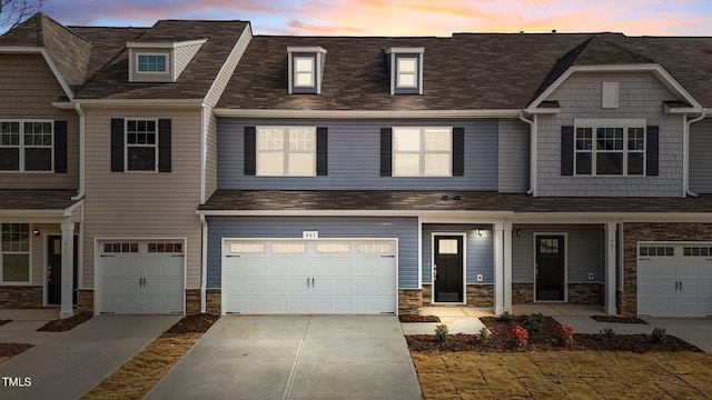 view of property with stone siding, driveway, and an attached garage