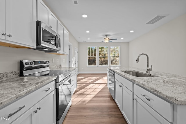 kitchen featuring visible vents, light wood-style floors, white cabinets, stainless steel appliances, and a sink