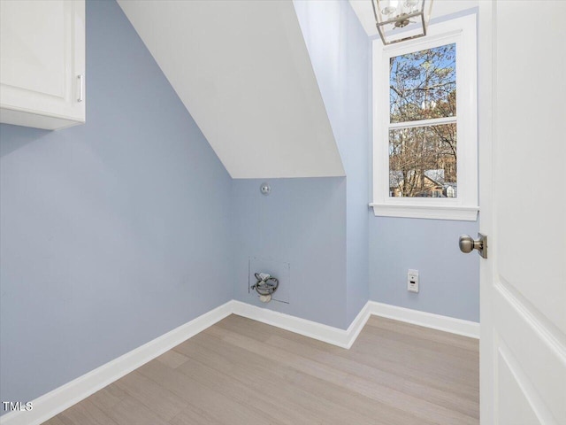 laundry room with cabinet space, baseboards, and light wood finished floors