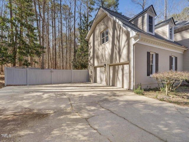 view of side of property with concrete driveway, a garage, fence, and brick siding