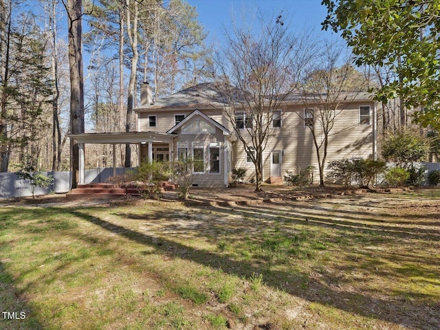 back of house featuring a yard and a chimney