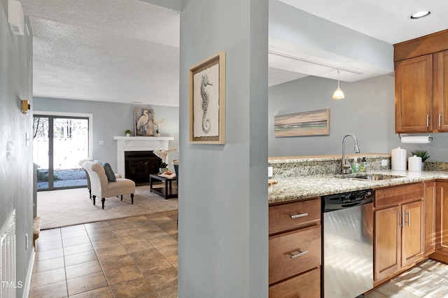 kitchen featuring light stone counters, brown cabinetry, a fireplace, a sink, and dishwasher