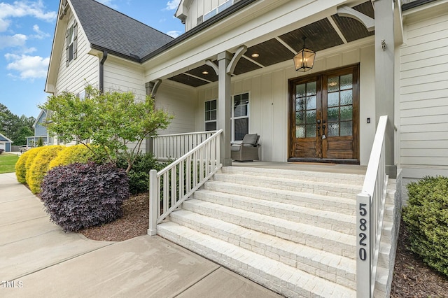 entrance to property featuring french doors, board and batten siding, covered porch, and a shingled roof