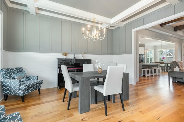 dining area featuring beamed ceiling, coffered ceiling, an inviting chandelier, and a decorative wall