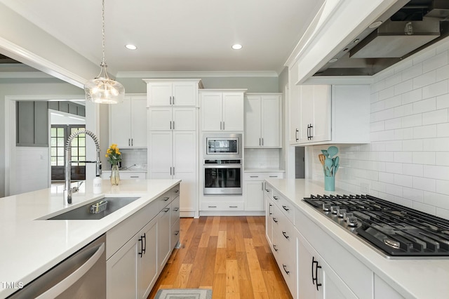 kitchen with under cabinet range hood, decorative light fixtures, light countertops, stainless steel appliances, and a sink