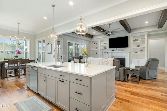 kitchen with light wood-type flooring, gray cabinets, a sink, a fireplace, and light countertops