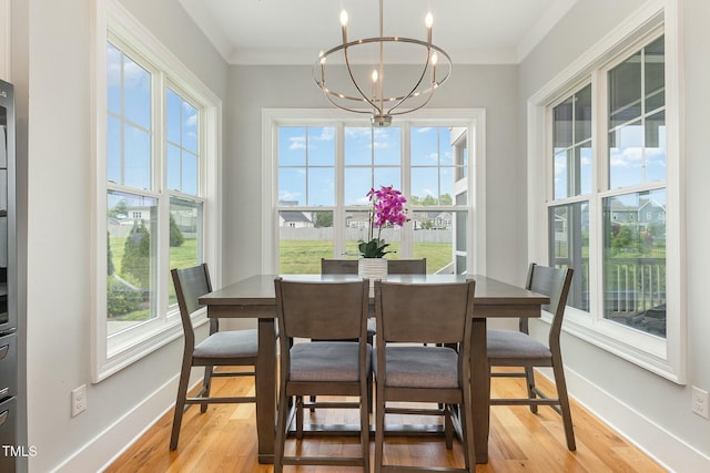 dining area featuring light wood-type flooring, baseboards, an inviting chandelier, and crown molding