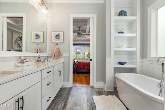 ensuite bathroom with ensuite bathroom, a sink, wood finished floors, double vanity, and a soaking tub