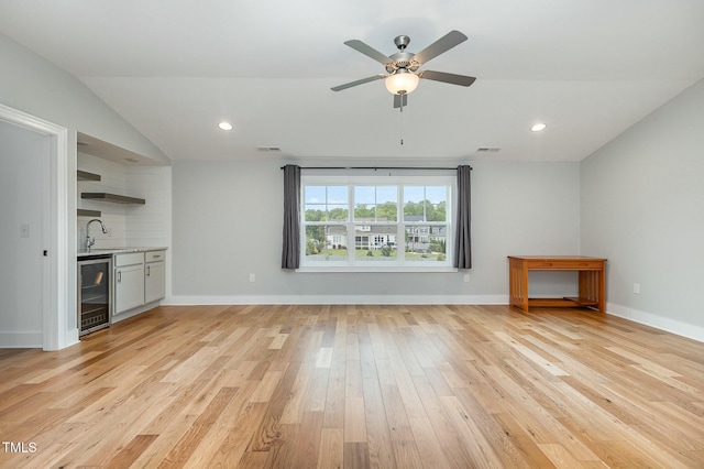 unfurnished living room featuring recessed lighting, light wood-type flooring, baseboards, and beverage cooler