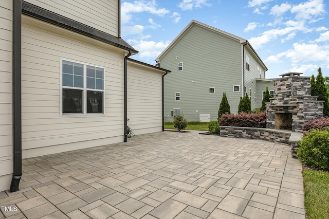 exterior space with an outdoor stone fireplace and a patio